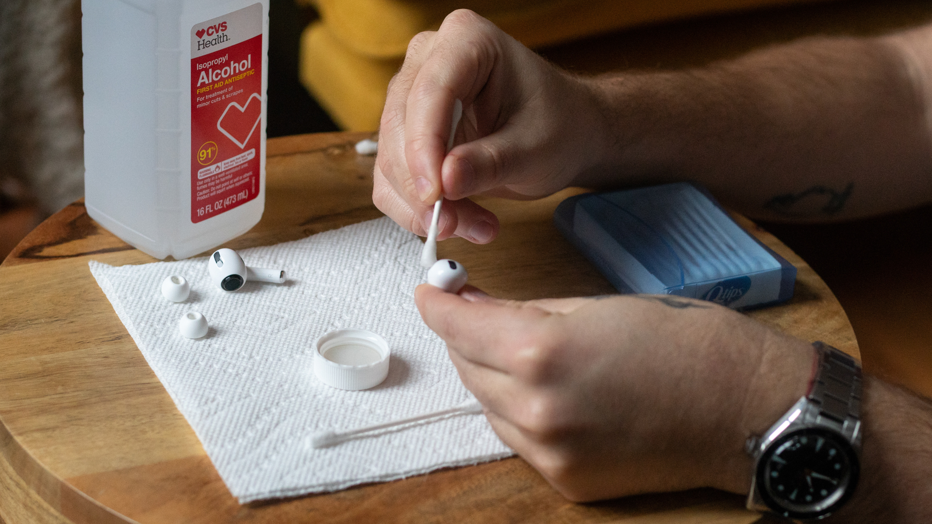 How to clean your AirPods Pro-6 A man holds a Q-tip to a pair of AirPods Pro earbuds as he cleans them with isopropyl alcohol.