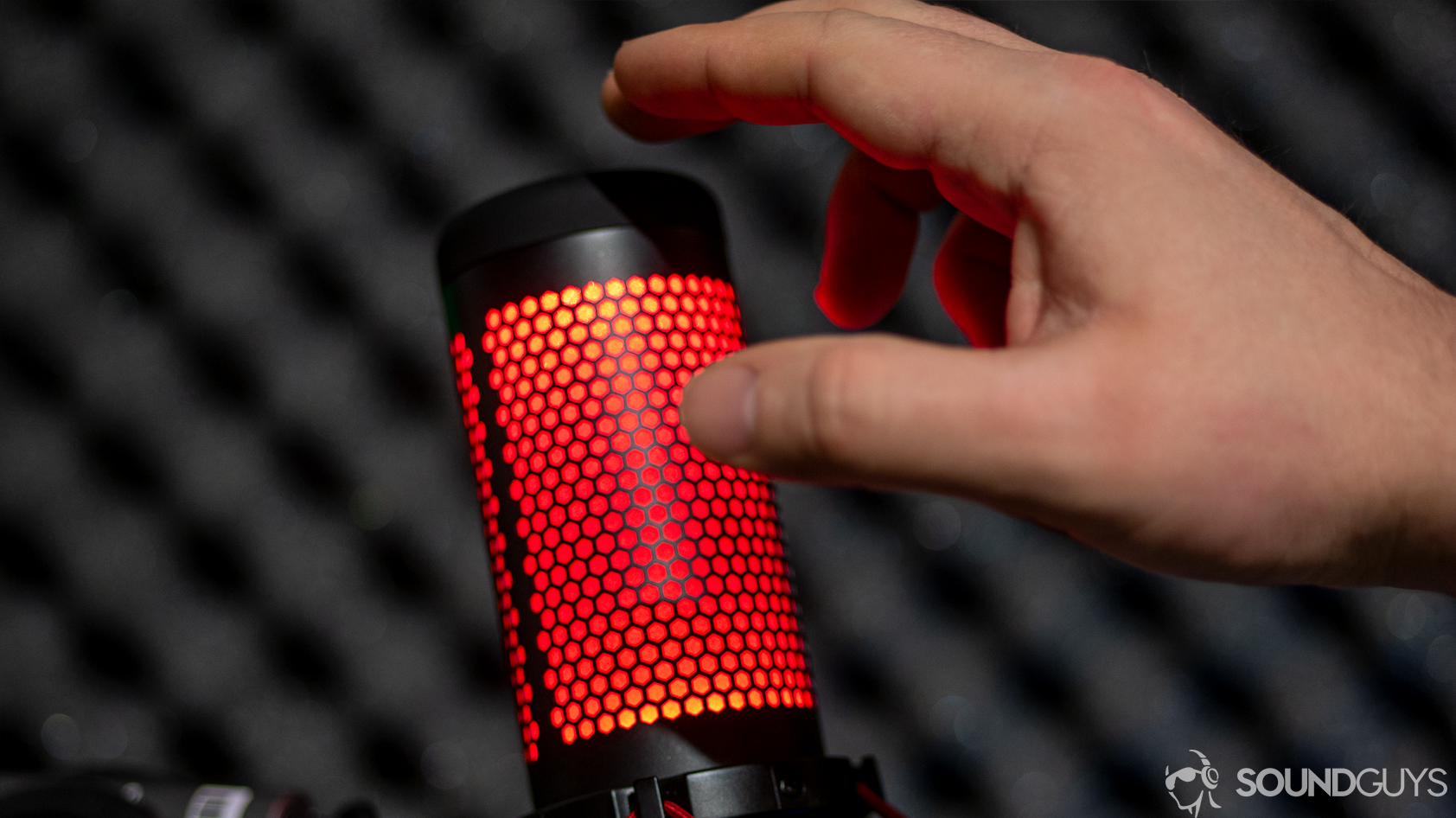 hyperx-quadcast-mute A man uses the HyperX QuadCast microphone mute switch on top of the capsule.