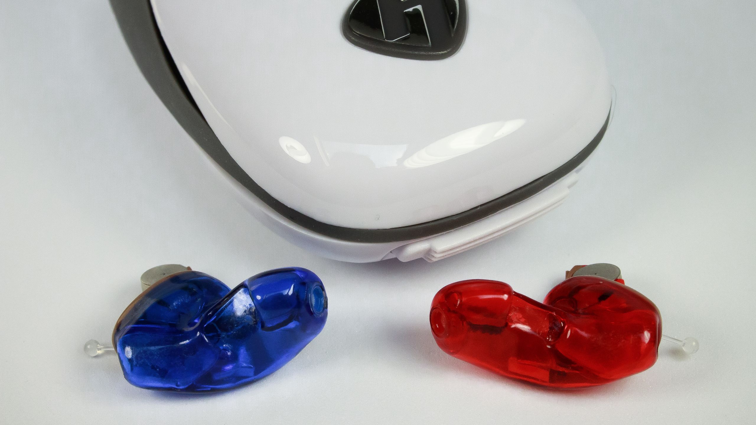 ITC Hearing Aids A pair of ITC hearing aids with exposed battery, laying next to a white case.