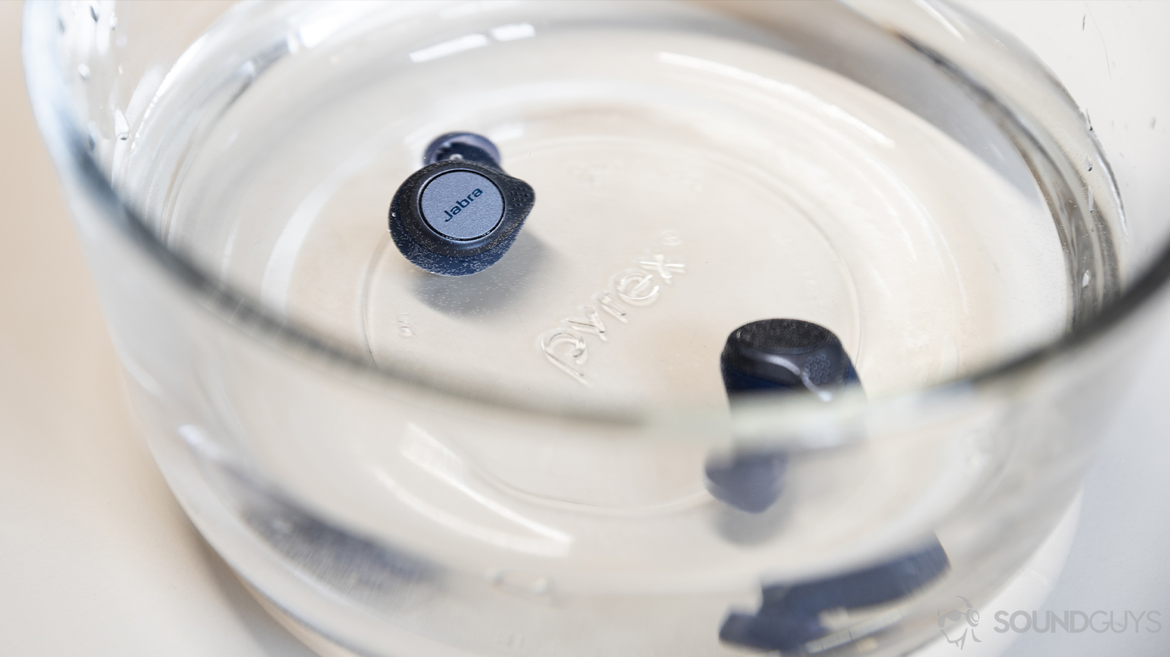 Jabra Elite Active 75t-true wireless workout earbuds waterproof submerge A picture of the Jabra Elite Active 75t true wireless workout earbuds (navy) submerged in a Pyrex bowl of water.