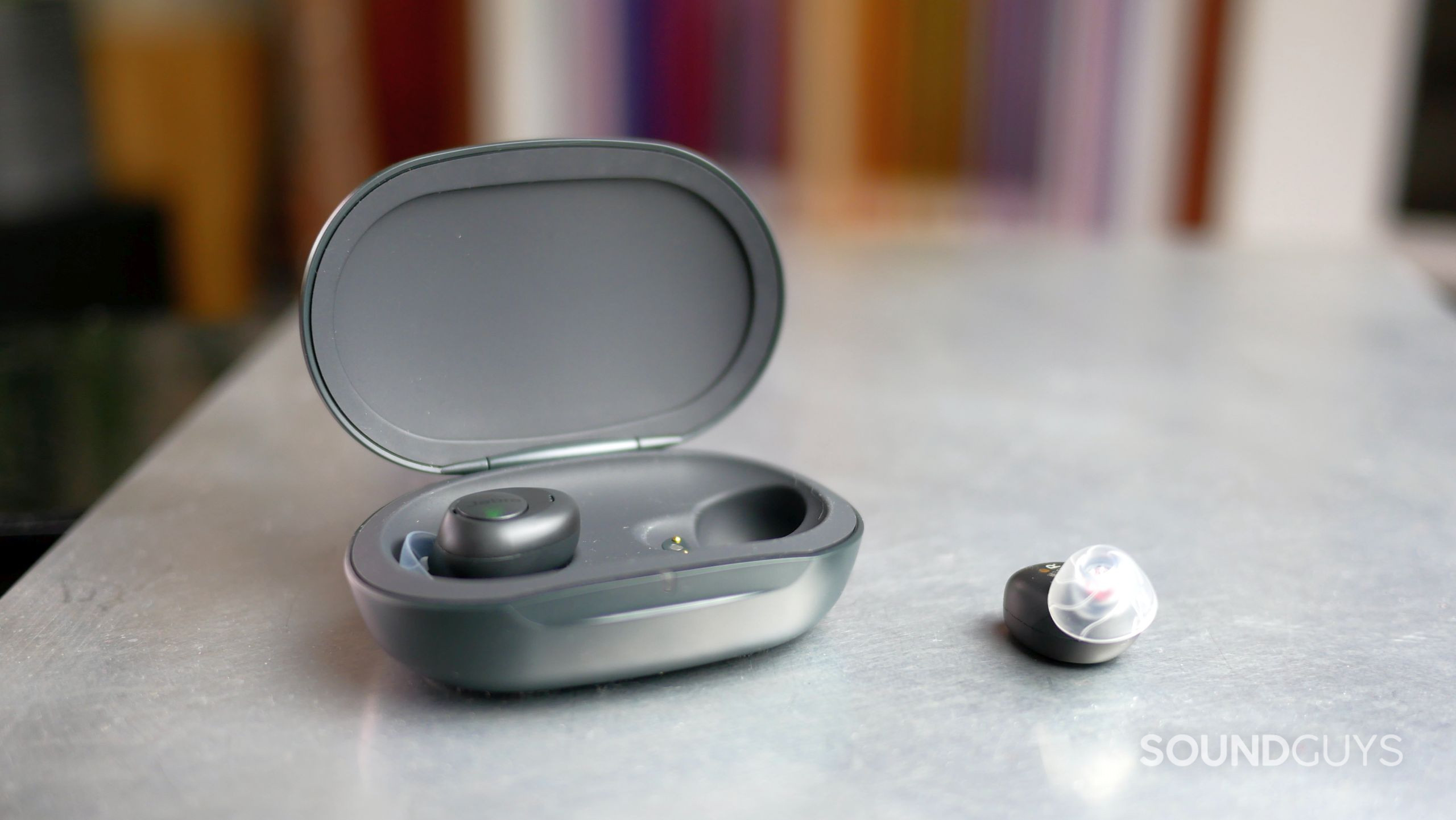Jabra Enhance Plus Earbuds and Open Case Jabra Enhance Plus open charging case with one earbud and a second lying next to it.