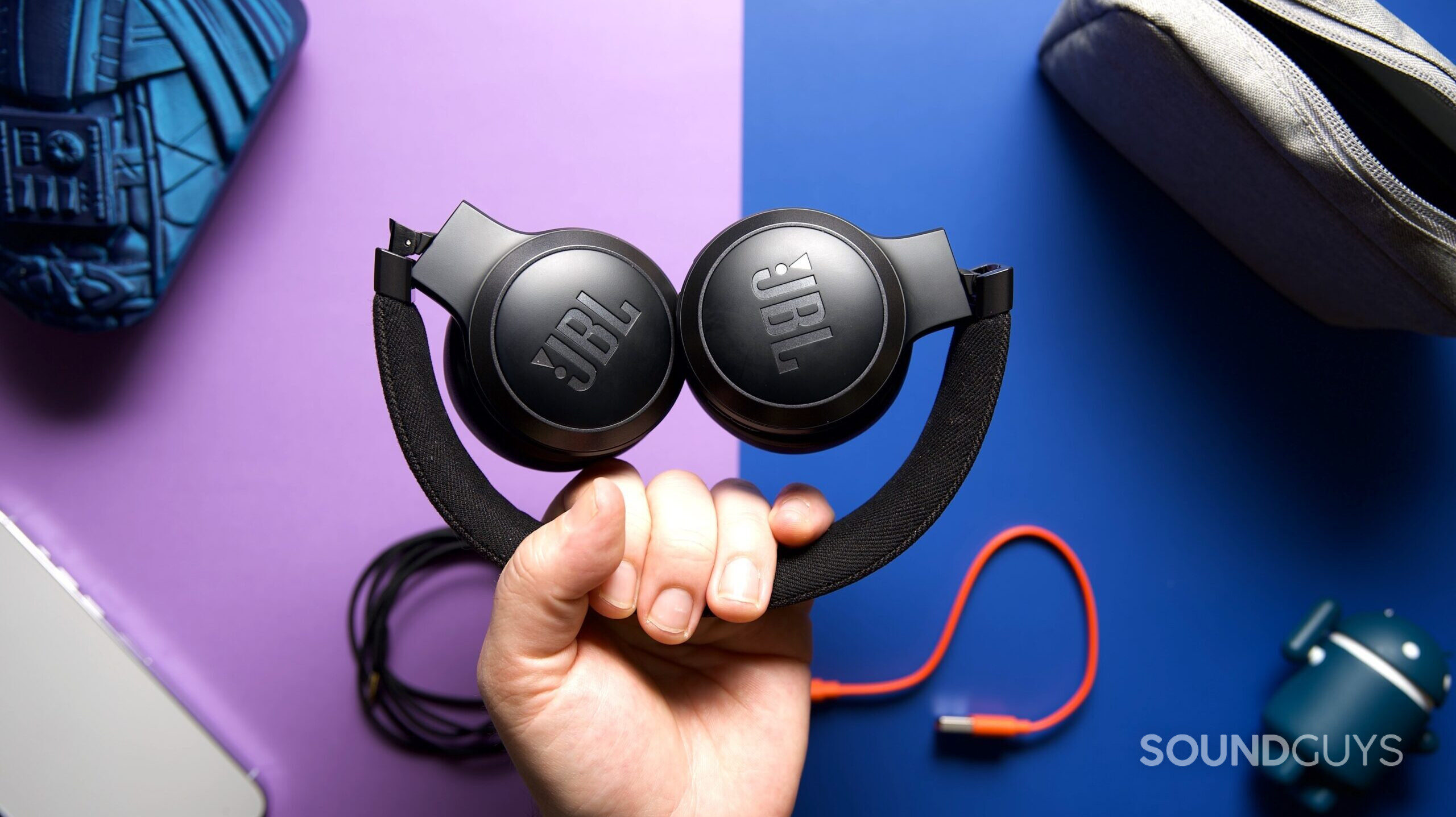 JBL Live 670NC 4 A hand holding a folded up pair of JBL Live 670NC headphones