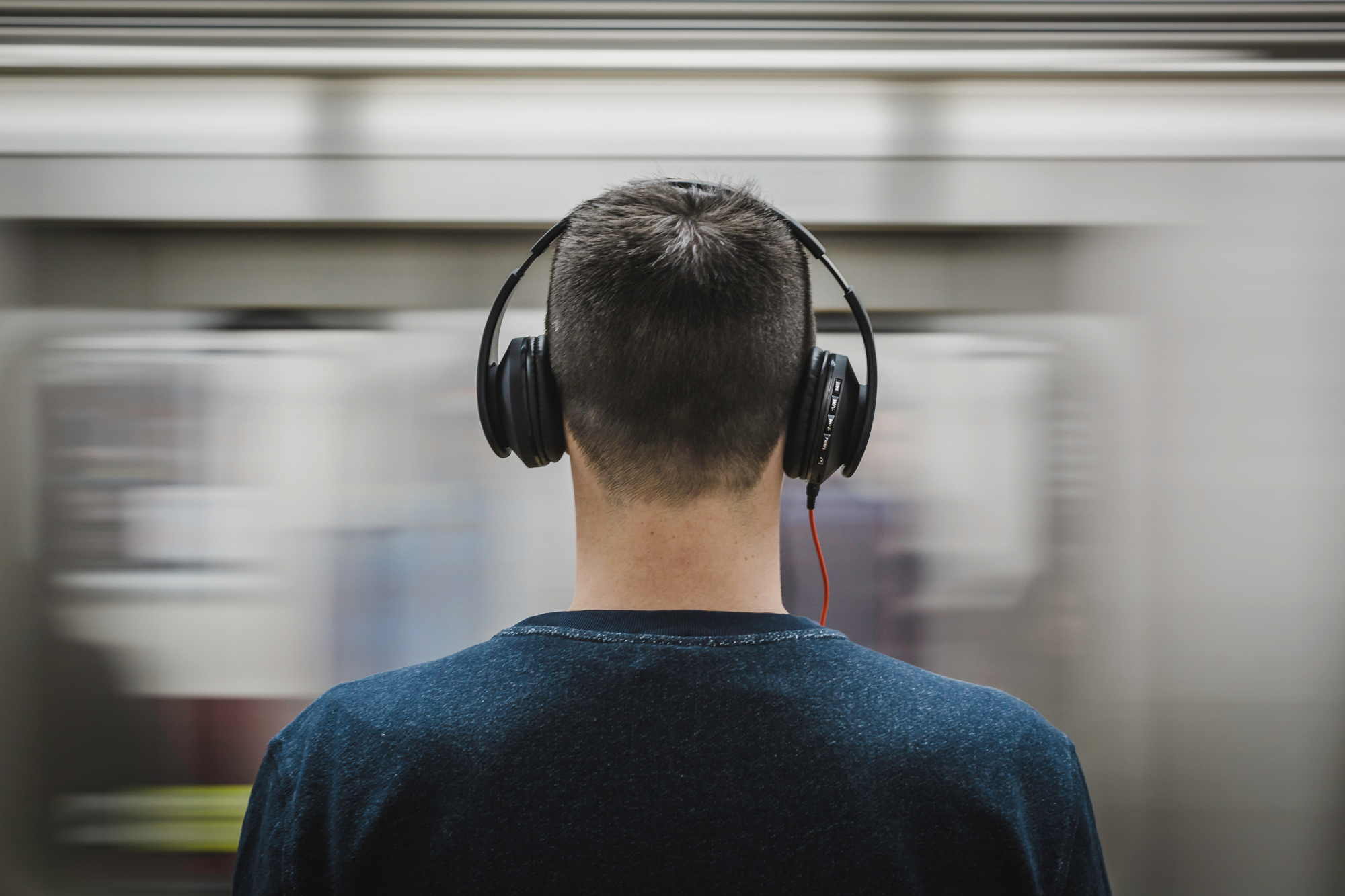 kids-headphones-subway A photo of a young man wearing headphones in front of a moving train, for the article "best headphones for kids."