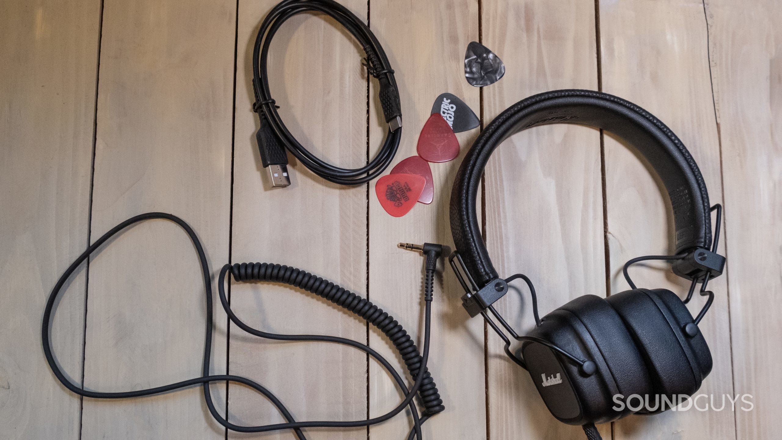 marshall-major-iv-accessories On a light wood surface are the cables and Marshall Major IV headphones.