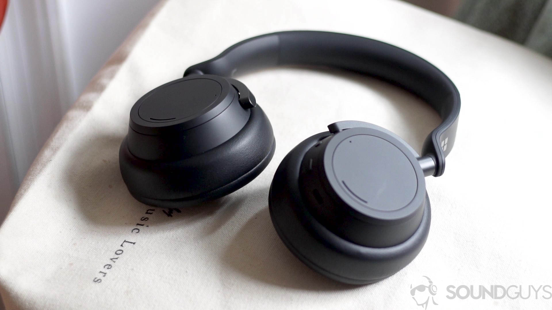 Microsoft Surface Headphones 2 lying flat Microsoft Surface Headphones 2 flat on a light brown tote bag