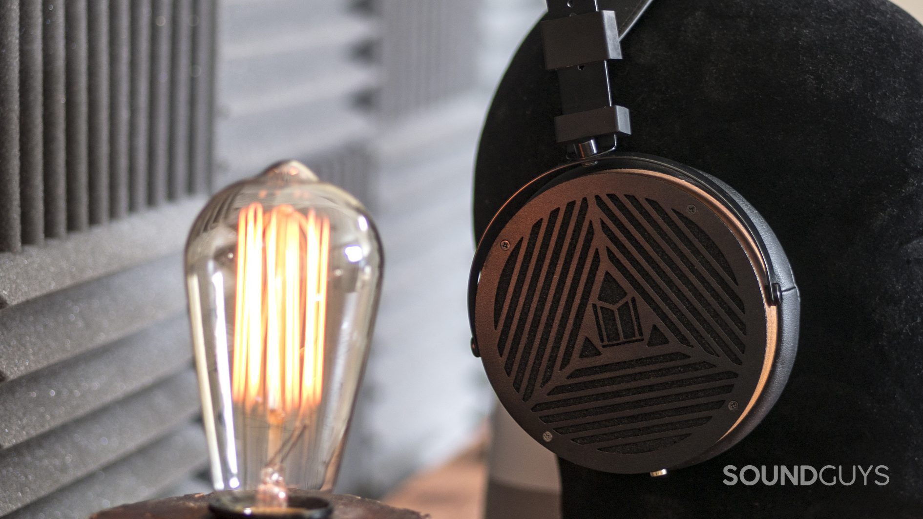 monoprice-monolith-m1060-review-hero The Monoprice Monolith M1060 open-back, over-ear headphones next to lightbulb.