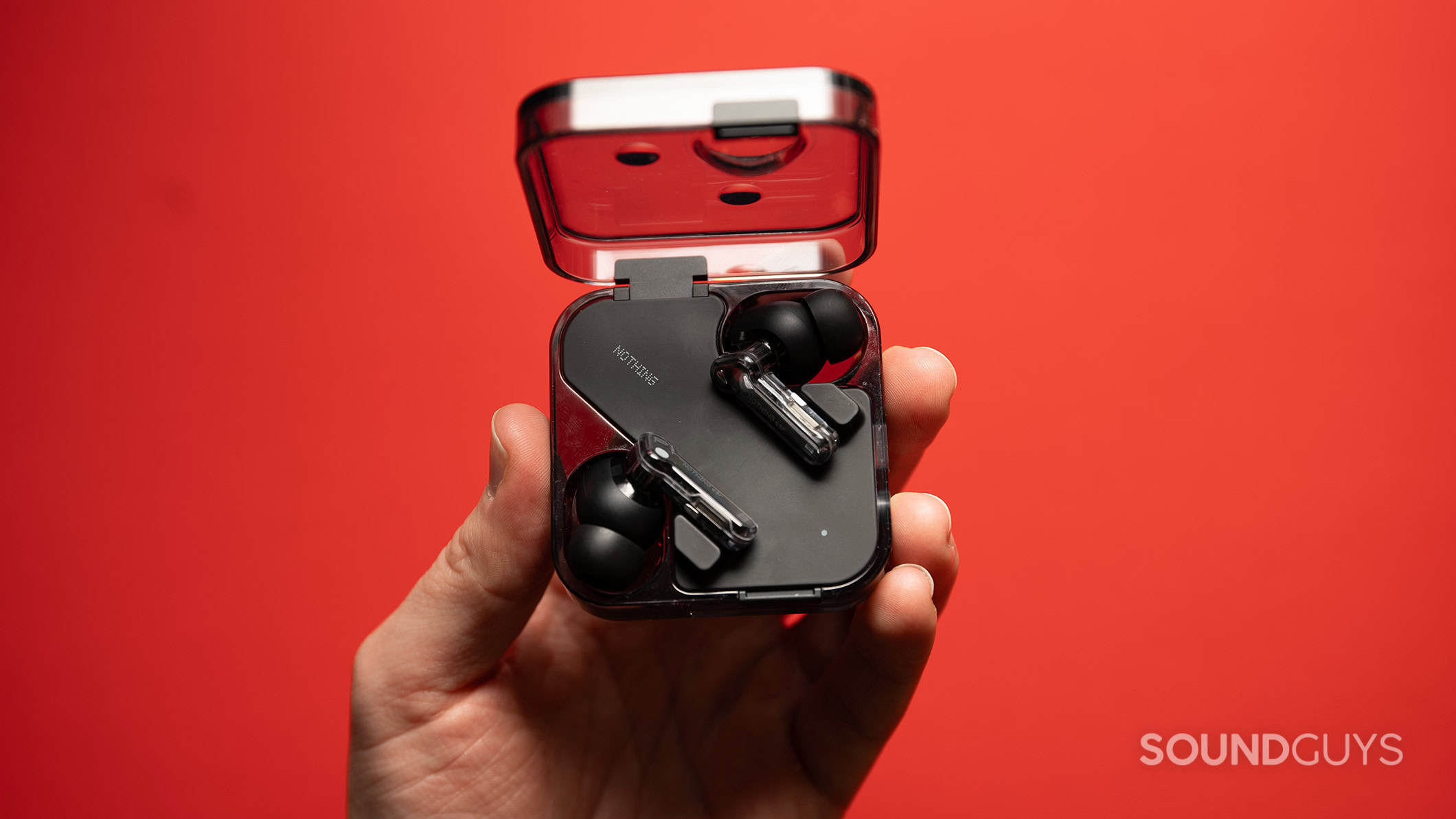 Nothing Ear hero A hand holds the Nothing Ear earbuds inside the case.