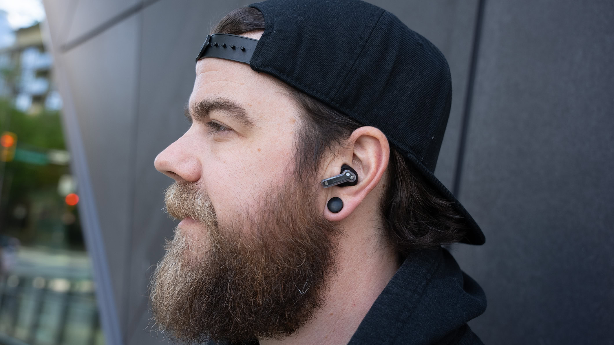 Nothing Ear in a mans ear Nothing Ear earbud in a man that is looking left.