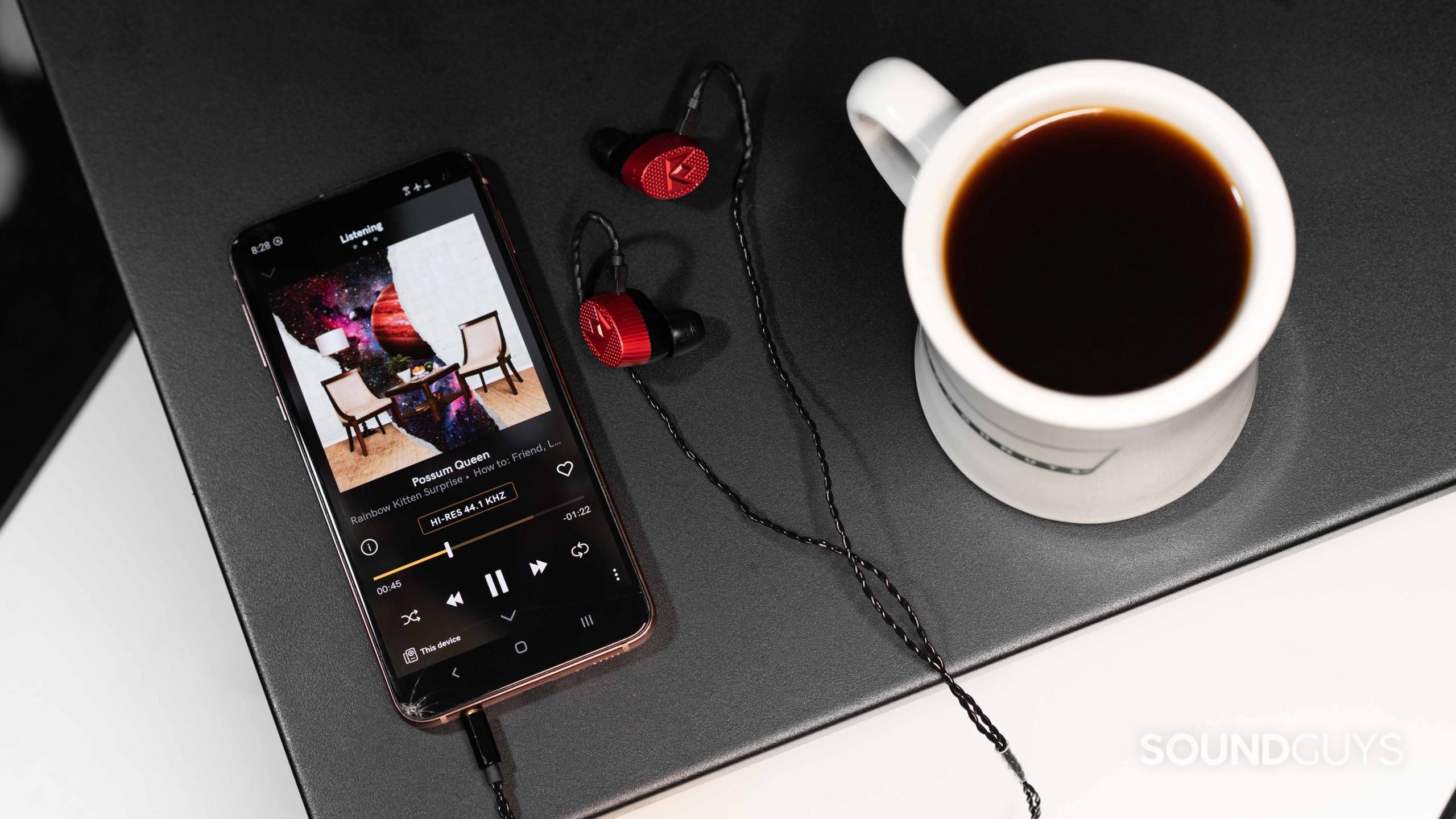 Qobuz music streaming Samsung Galaxy S10e Noble Audio Kaiser 10 earbuds- (1) The Qobuz music streaming service app's Listening tab open on a Samsung Galaxy S10e smartphone next to a pair of Massdrop x Noble Kaiser 10 IEMs and a cup of coffee.