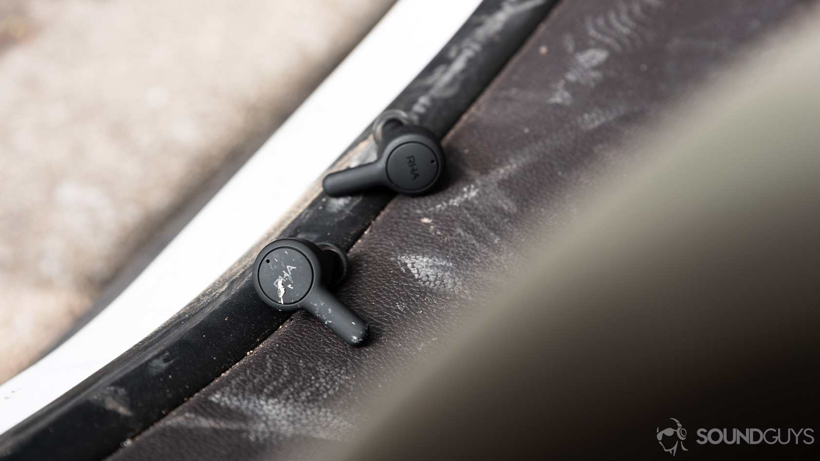 RHA TrueConnect 2-true wireless earbuds durable ip rating dust dirt A picture of the RHA TrueConnect 2 true wireless earbuds on a dirty surface with dirt on the earbuds.