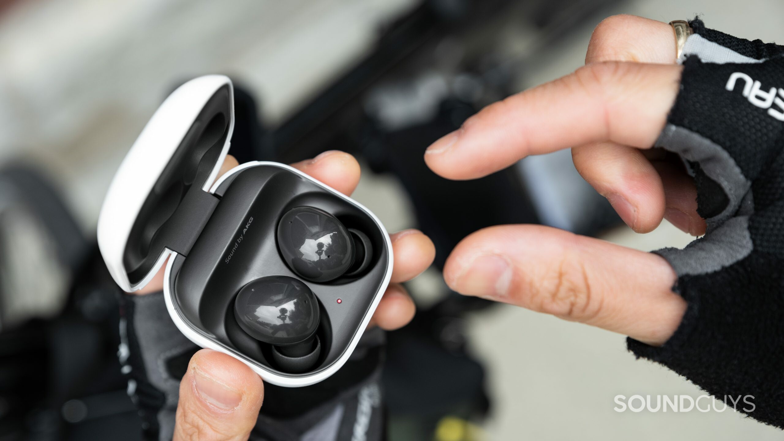 Samsung Galaxy Buds 2-noise canceling true wireless- (2) A hand reaches to remove one Samsung Galaxy Buds 2 noise canceling true wireless 2 earbud from the case.