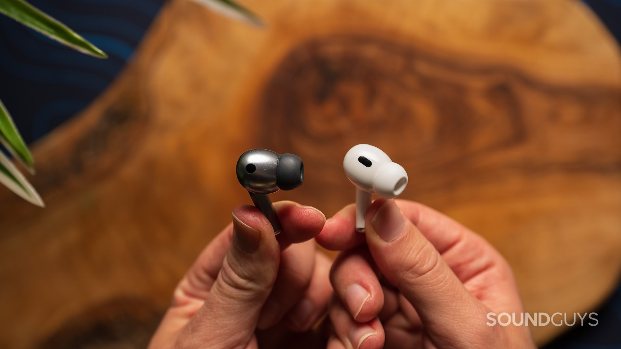 Samsung Galaxy Buds3 Pro vs Apple AirPods Pro (2nd generation) earbuds 3 A hand holds a Samsung Galaxy Buds3 Pro earbud and a Apple AirPods Pro (2nd generation) earbud.