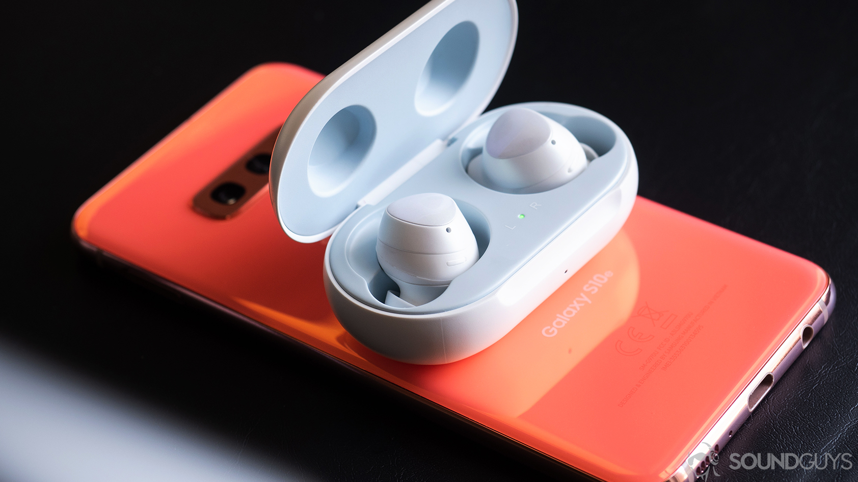 Samsung_Galaxy Buds-4 A picture of the Samsung Galaxy Buds earbuds in the case on top of a Samsung Galaxy S10e in Flamingo Pink.