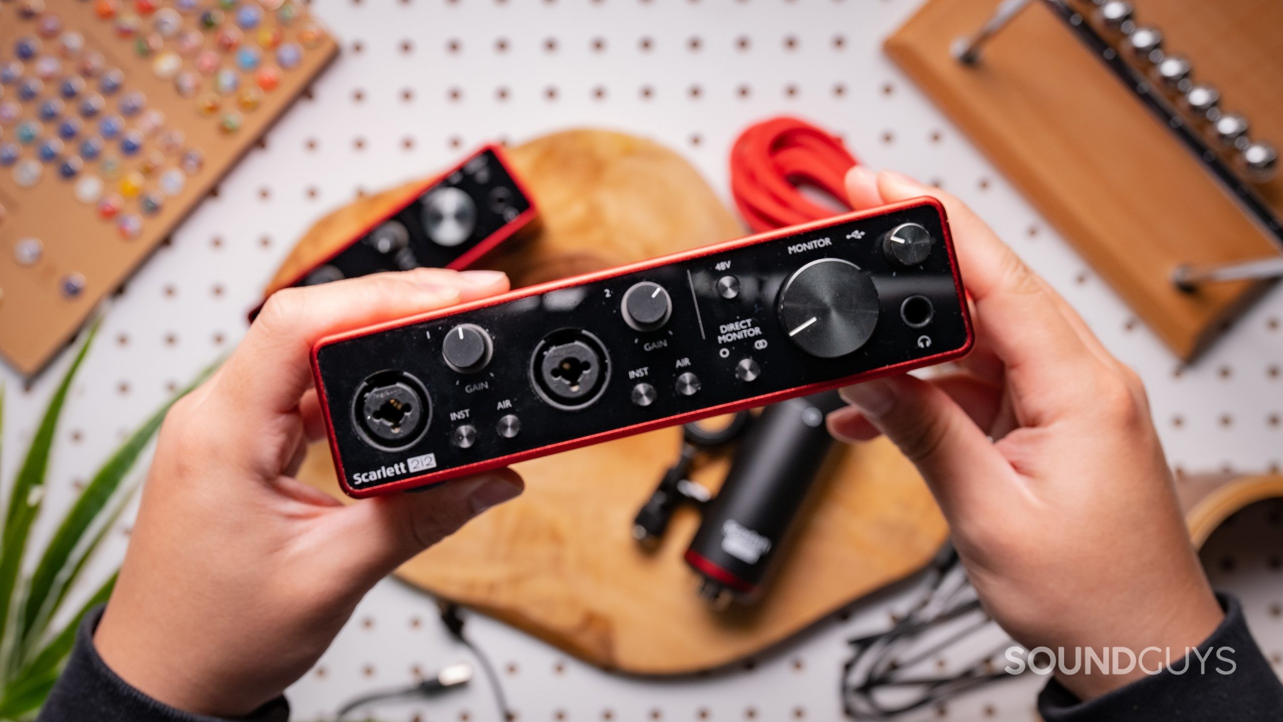 Scarlett Pro Bundle Mixer Image #1 The Focusrite Scarlett 2i2 is held above a Focusrite Scarlett Solo.