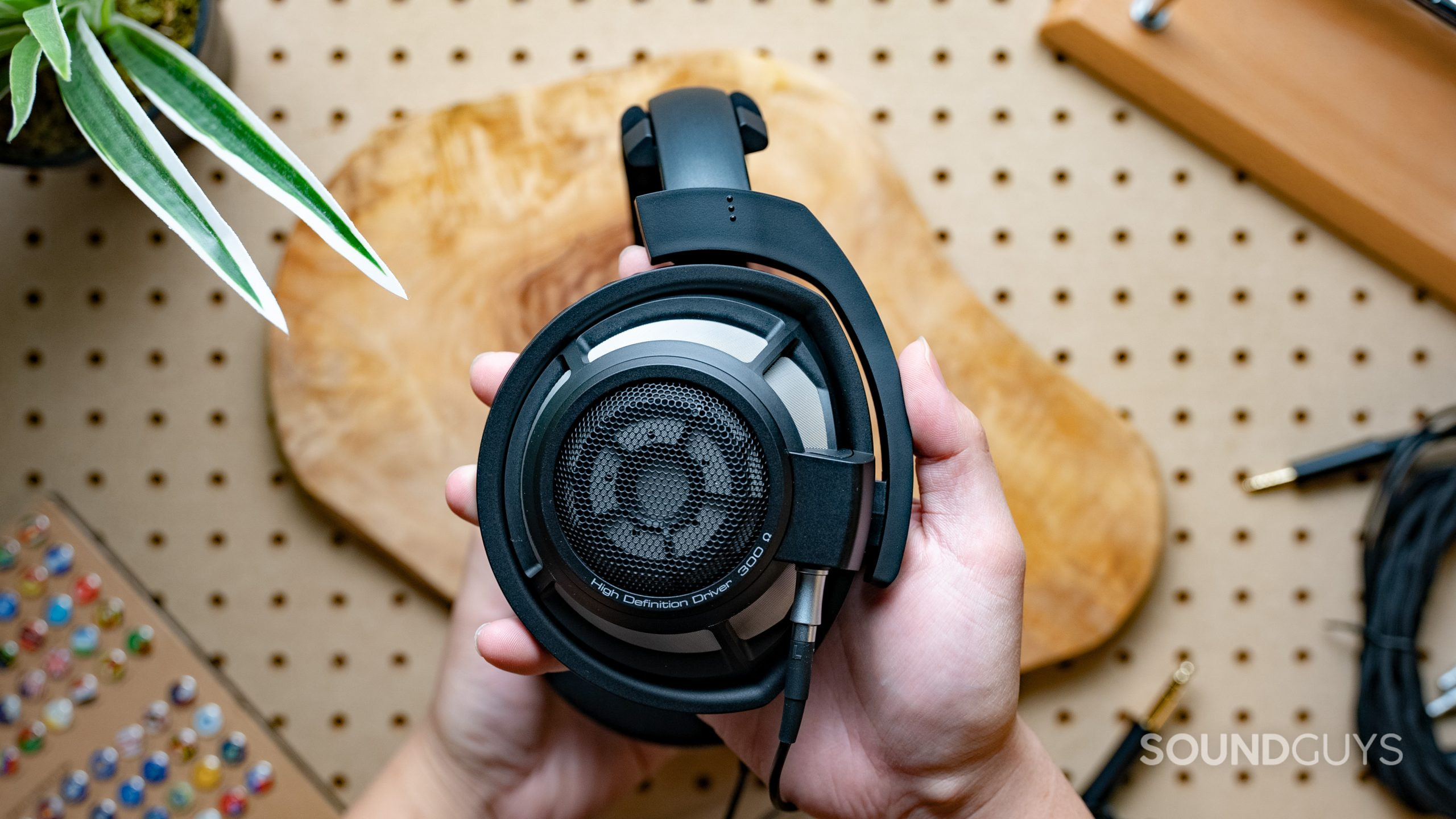 Sennheiser HD800 Featured Image #3 A photo of the Sennheiser HD 800 S being held in front of pegboard.