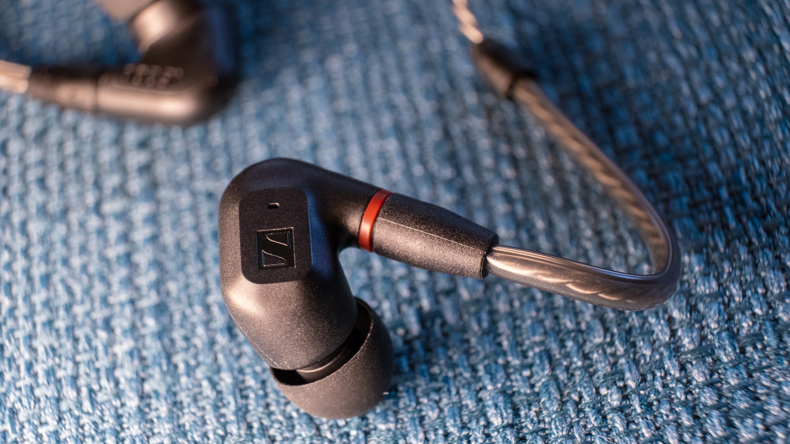 sennheiser-ie-200-close-up A macro close up of the right Sennheiser IE 200 bud rests on teal fabric.