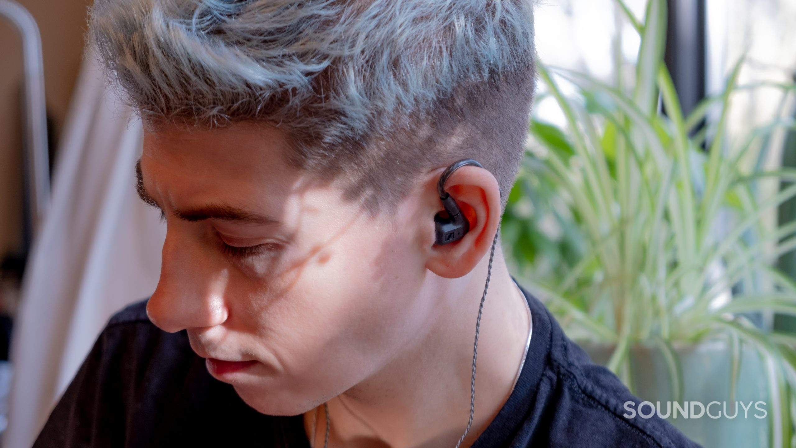 sennheiser-ie-200-in-ears A man wears the Sennheiser IE 200 IEMs with an aloe plant in the background.