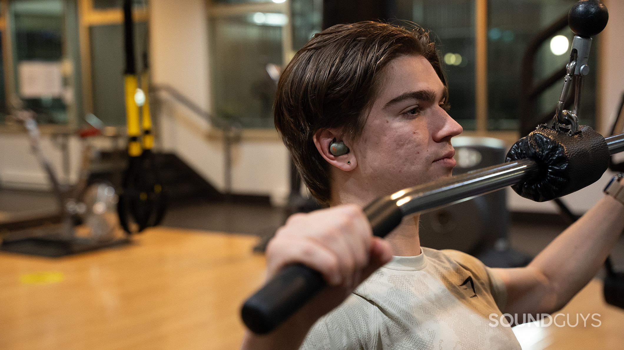 Sennheiser MOMENTUM Sport workout 2 A man wearing the Sennheiser MOMENTUM Sport earbuds while exercising in a gym.