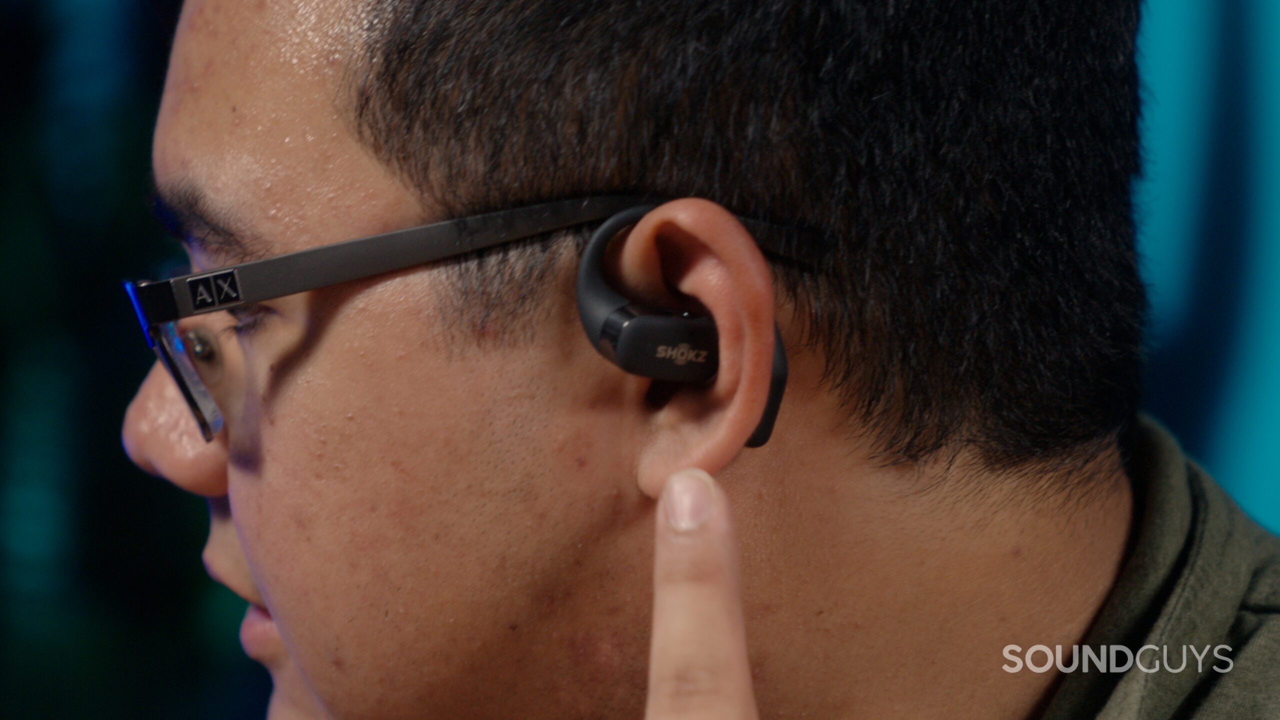 Shokz OpenFit in ears A man faces left wearing the Shokz OpenFit about to use the touch control.