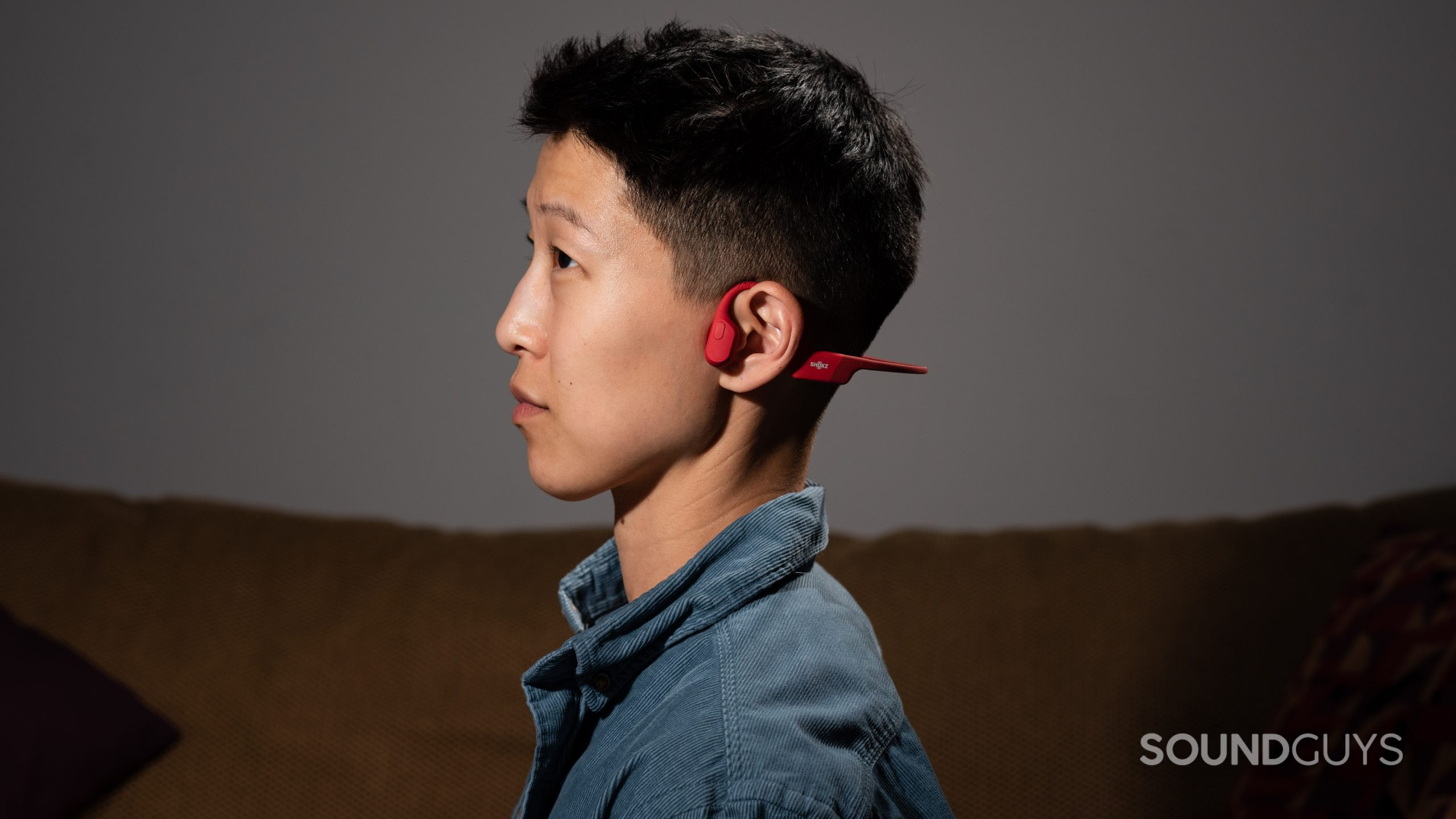Shokz OpenRun pereson wears bone conduction headphones A woman wears the Shokz OpenRun bone conduction headphones in red.
