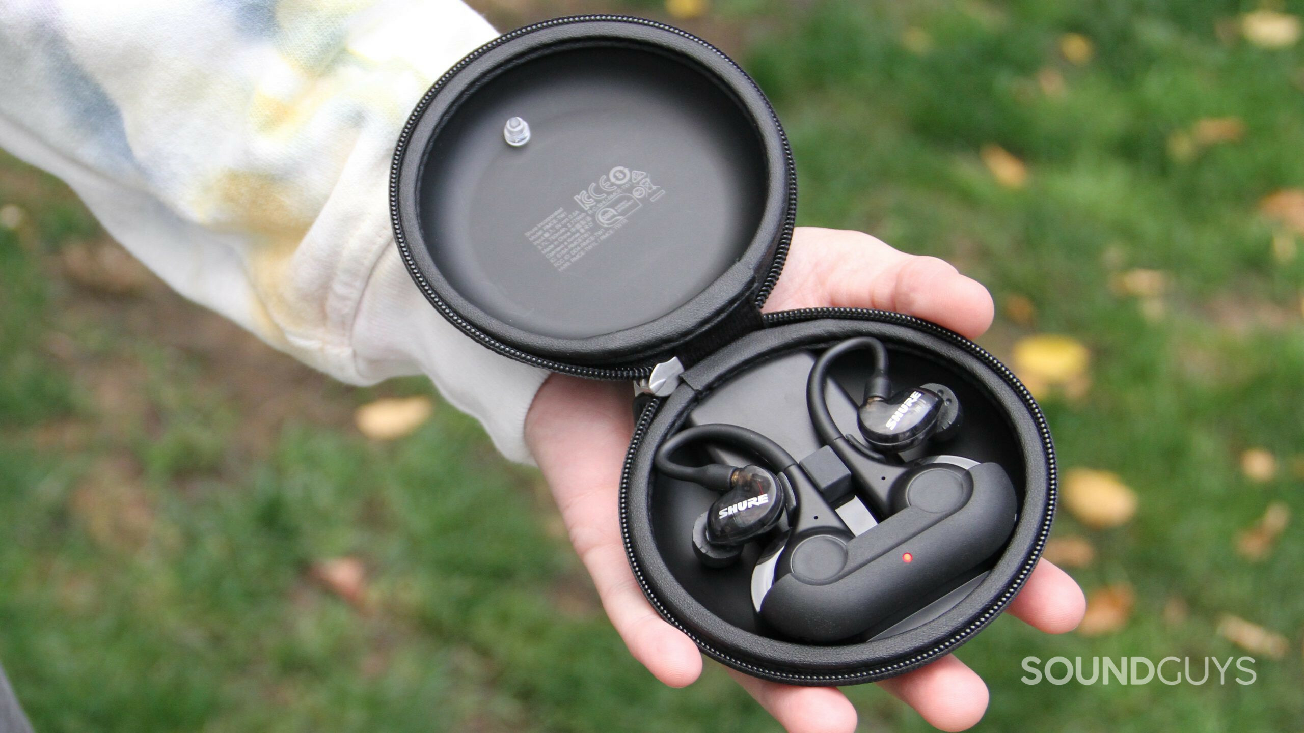 shure-aonic-215-gen-2-open-case A hand holds the open battery case with the Shure AONIC 215 Gen 2 earphones inside.