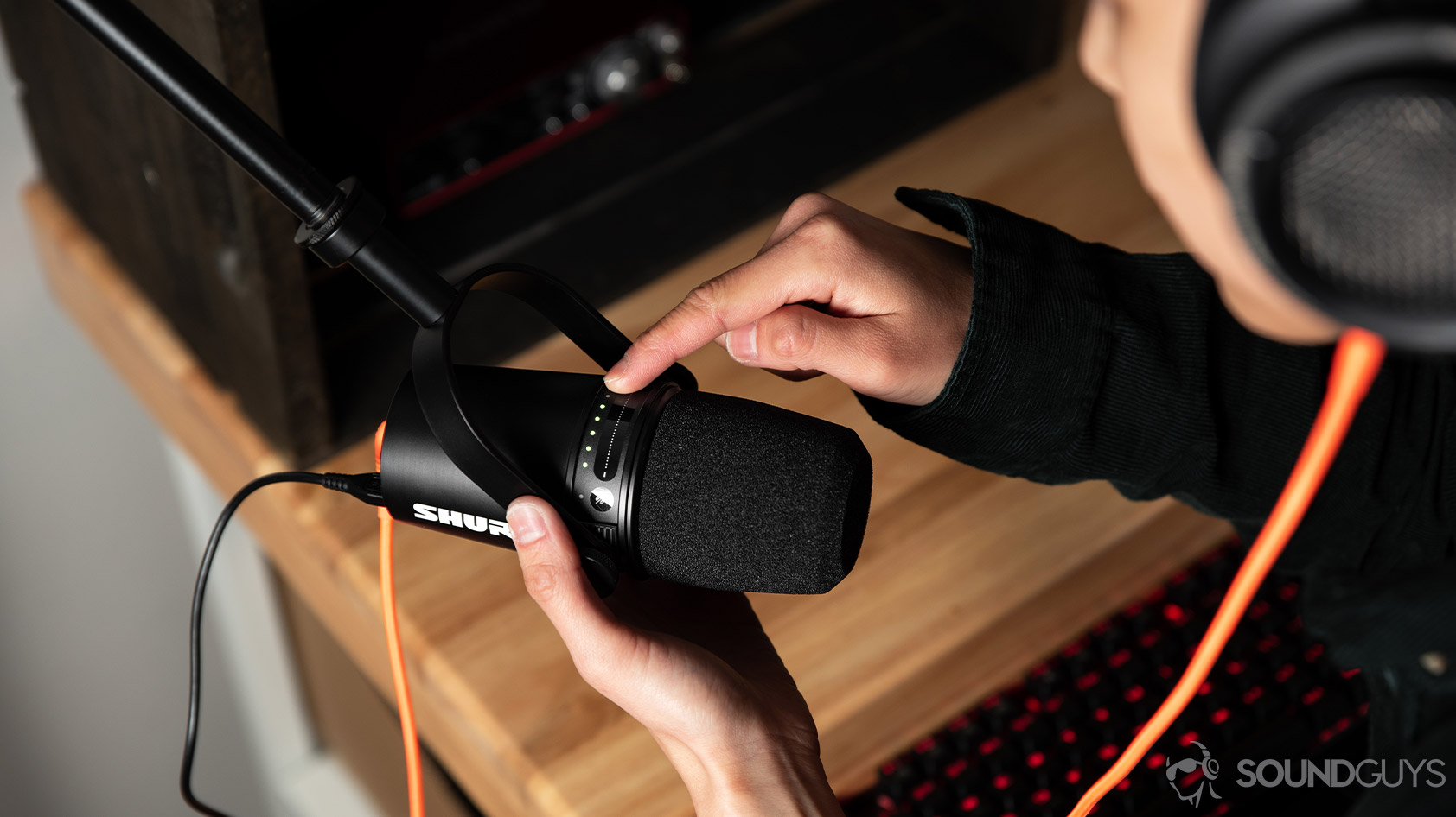 Shure MV7 USB microphone XLR touch controls A person uses the Shure MV7 microphone touch controls to adjust the gain while she monitors the recording.