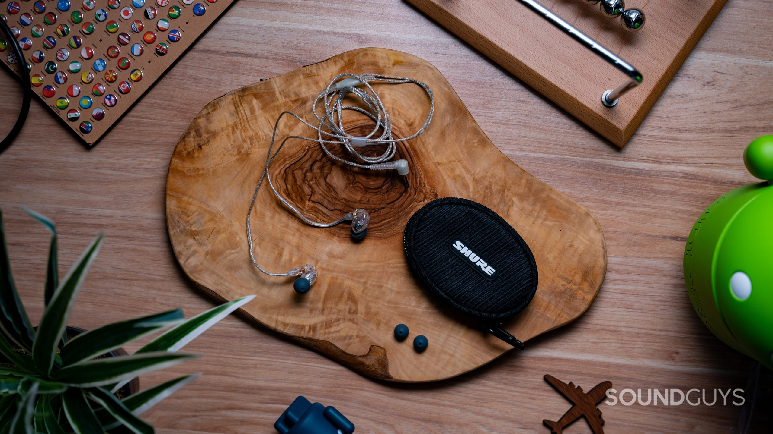 SHURE_SE215-#1 On a wood surface the Shure SE215 rests with its case, an extra set of ear tips.