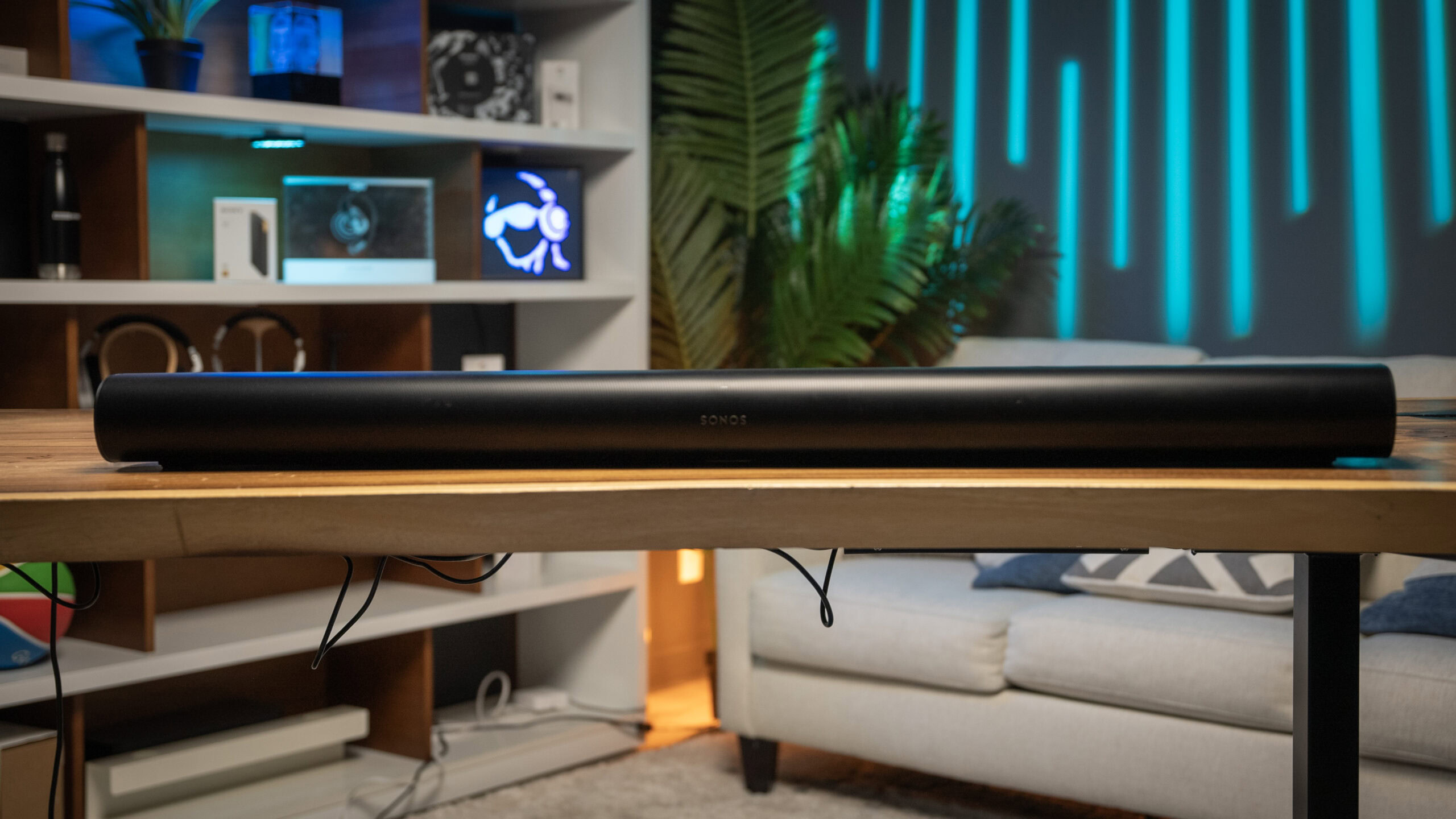 Sonos-Arc-Soundbar-On-Table-Hero-Front The Sonos Arc soundbar is placed on a wooden table in the middle of a brightly-colored studio setup.