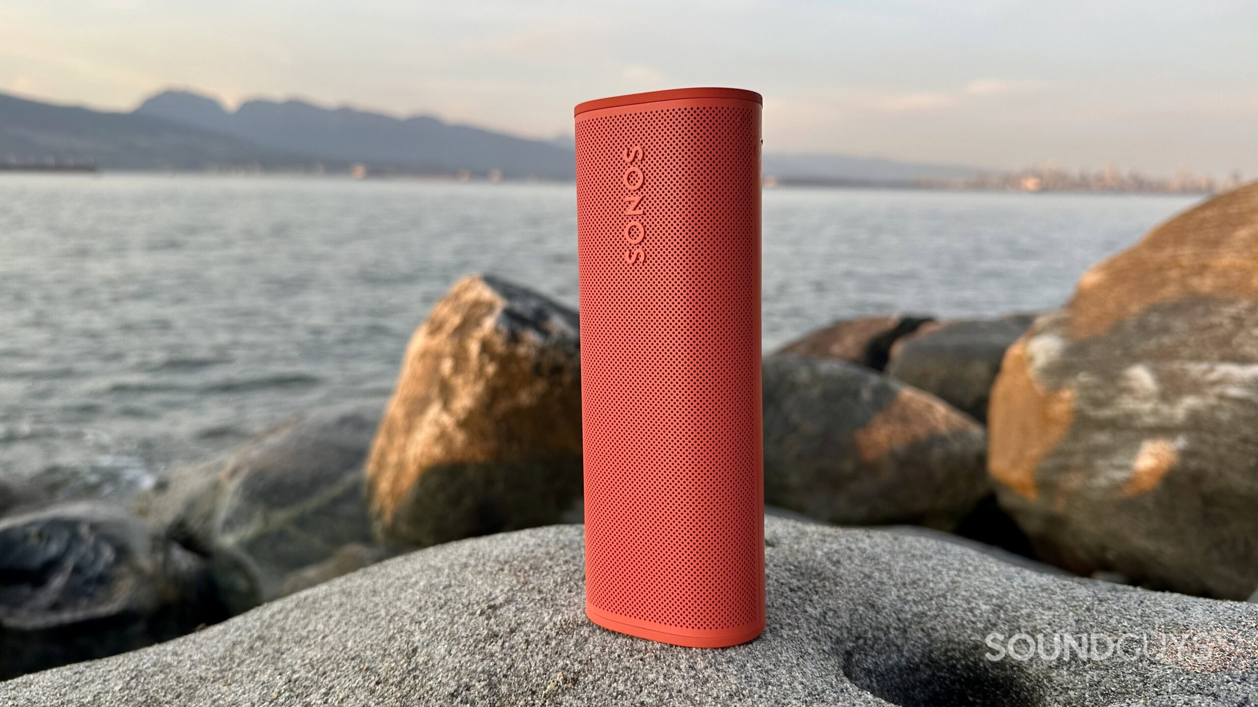 Sonos Roam 2 verticle A Sonos Roam 2 placed vertically on a rock near the ocean.