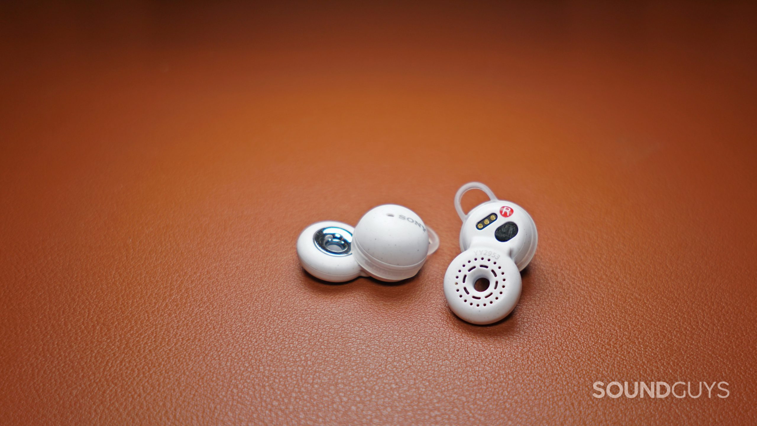 Sony-Linkbuds-close-up-on-leather-2 The Sony LinkBuds earbuds lay on a leather surface.