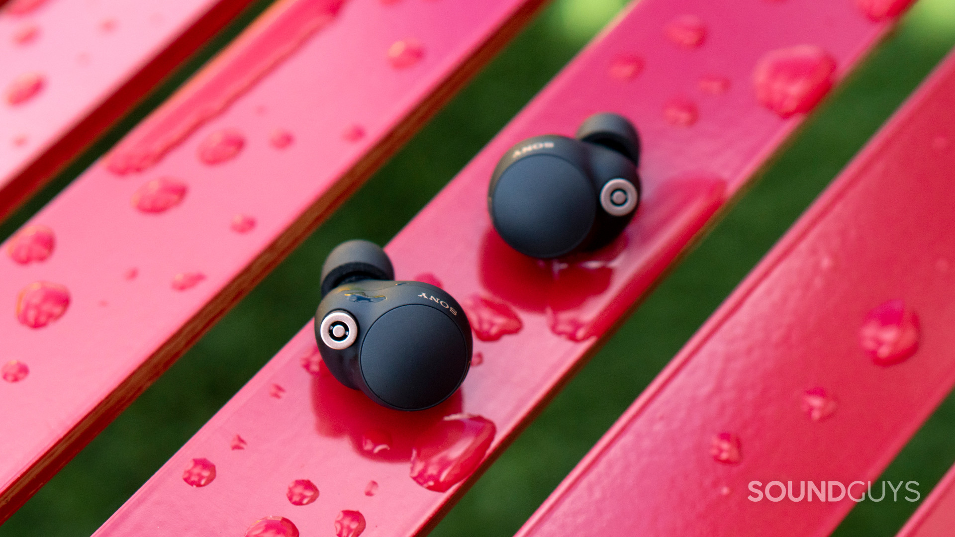 sony-wf-1000xm4-review-hero The Sony WF-1000XM4 on a wet, red bench, also with moisture on the earphones.