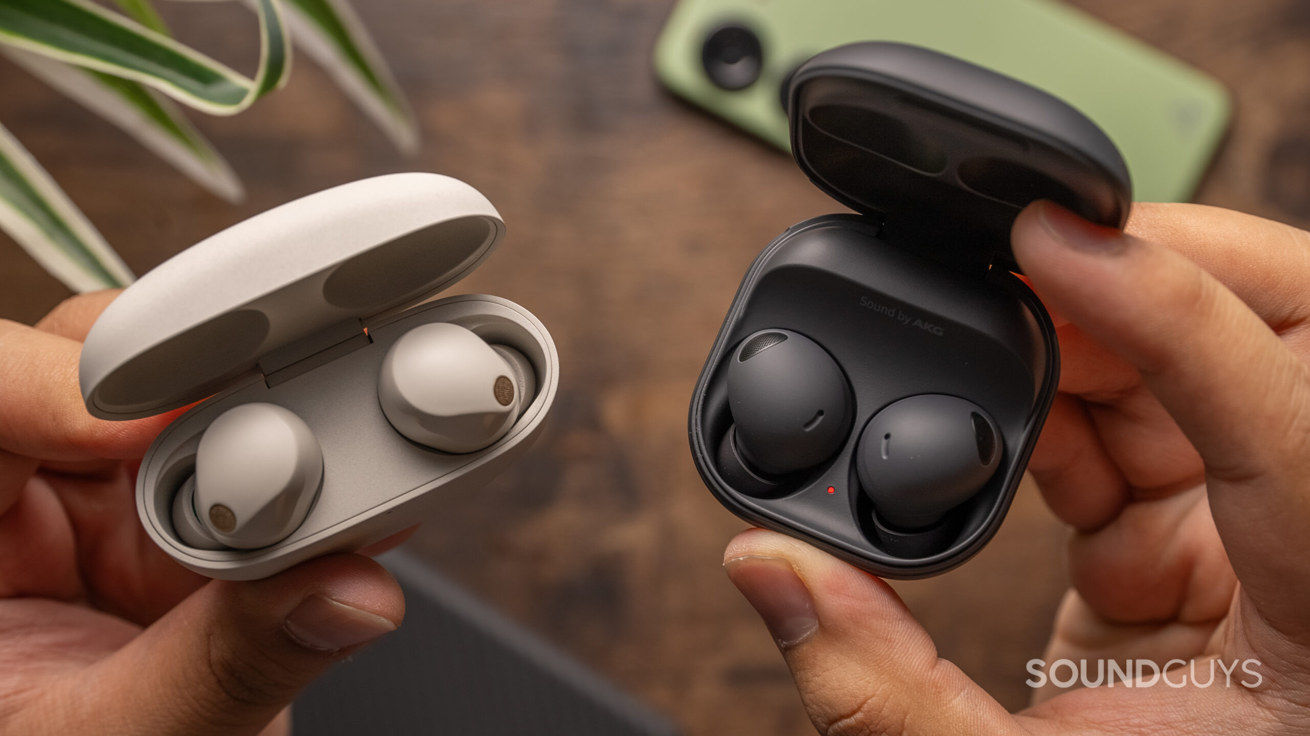 Sony WF-1000XM5 vs. Samsung Galaxy Buds 2 Pro earbuds inside charging case Two hands hold the open cases of the Sony WF-1000XM5 and Samsung Galaxy Buds 2 Pro.