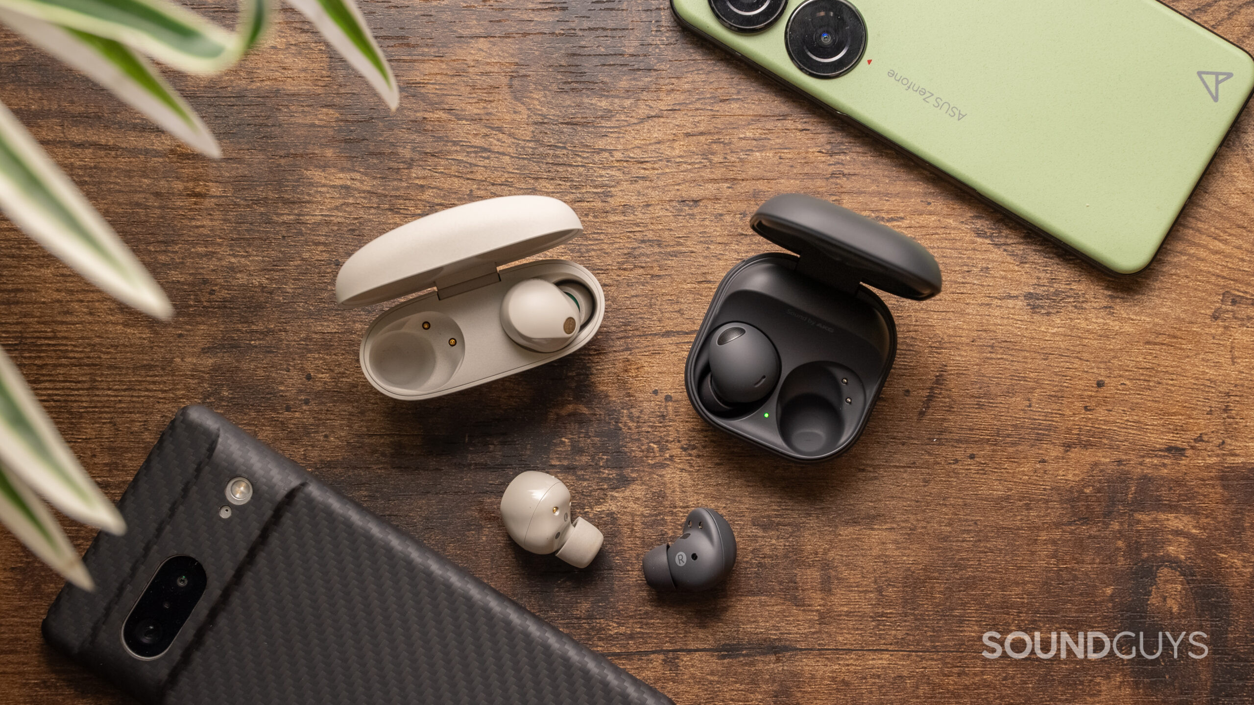 Sony WF-1000XM5 vs. Samsung Galaxy Buds 2 Pro one earbud outside of charging case The Sony WF-1000XM5 and Samsung Galaxy Buds 2 Pro rest on a wood surface with one bud of each outside of the case.