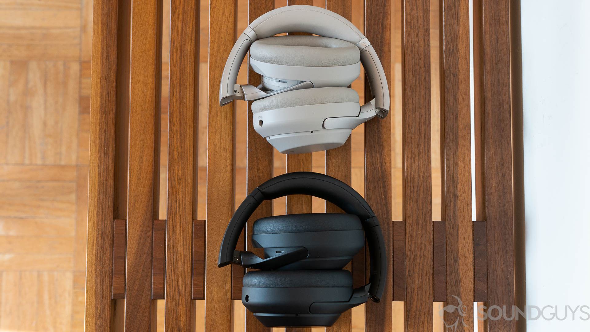 Sony WH-1000XM4 (3 of 4) The Sony WH-1000XM3 and Sony WH-1000XM4 lay folded up on a wooden bench.