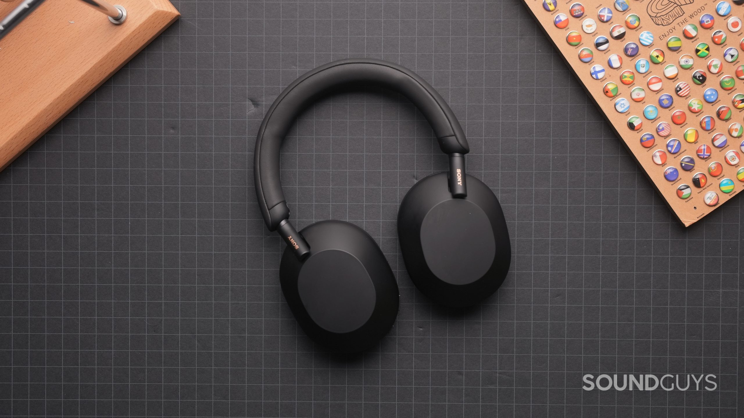 Sony WH-1000XM5 flat ear cups down Top-down view of the Sony WH-1000XM5 folded flat on a dark grey table