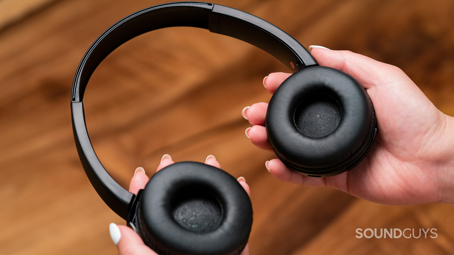 Sony WH-CH510 wireless on-ear headphones ear pads hand holds Hands hold Sony WH-CH510 wireless on-ear headset with the headphones facing up so the ear pads are visible.