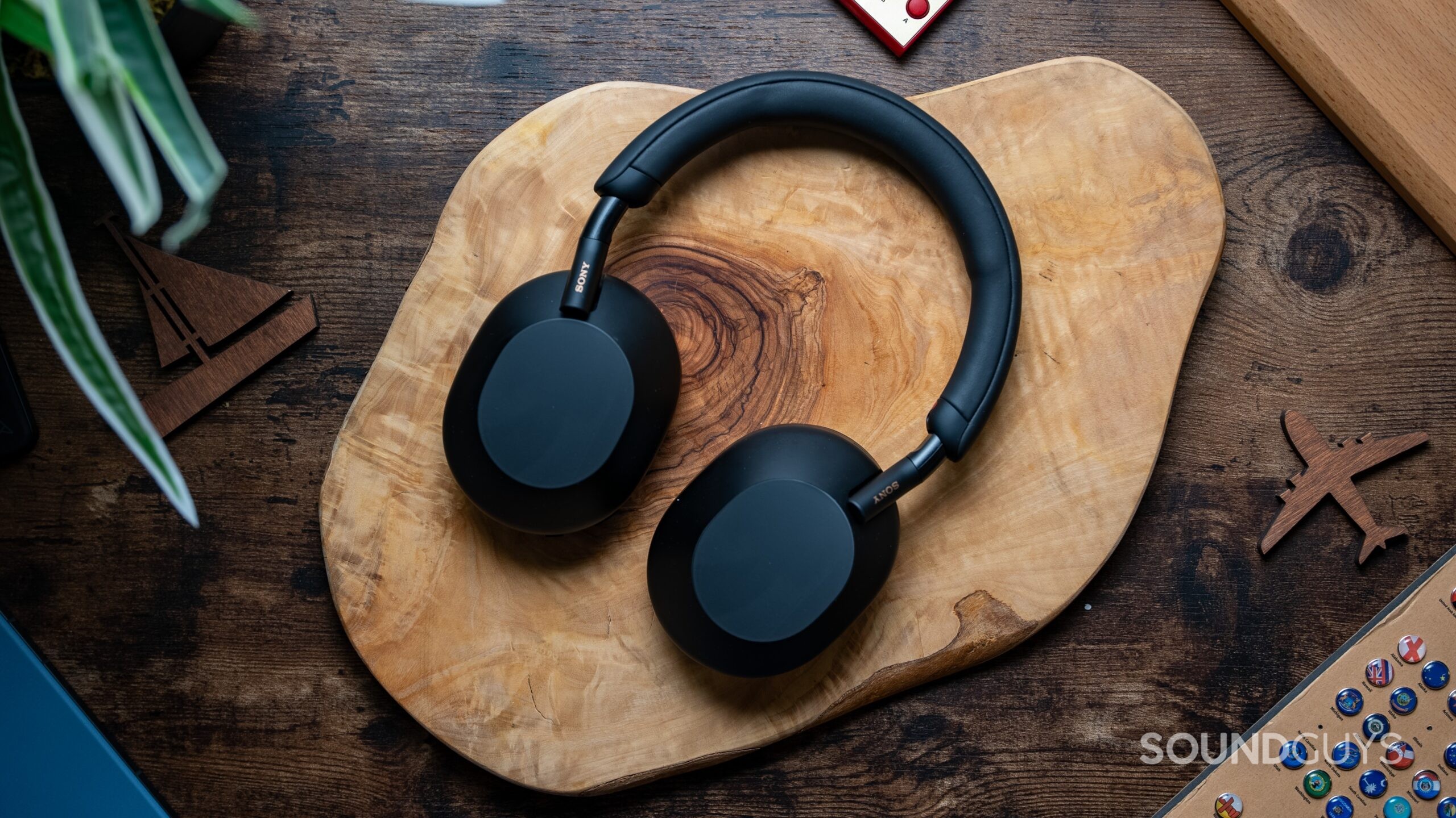 Sony WXM5 Headphones Featured Image #1 Sony WH-1000XM5 headphones laying flat on wooden table.