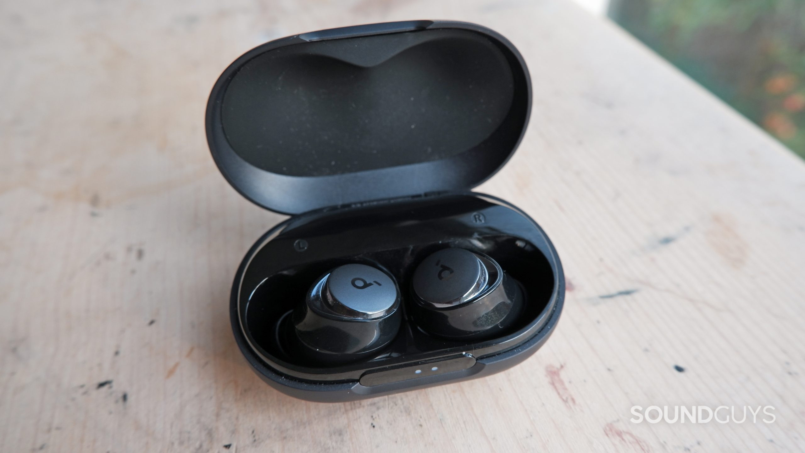 space-a40-buds-in-case-table The Anker Soundcore Space A40 inside its case on a wooden table.